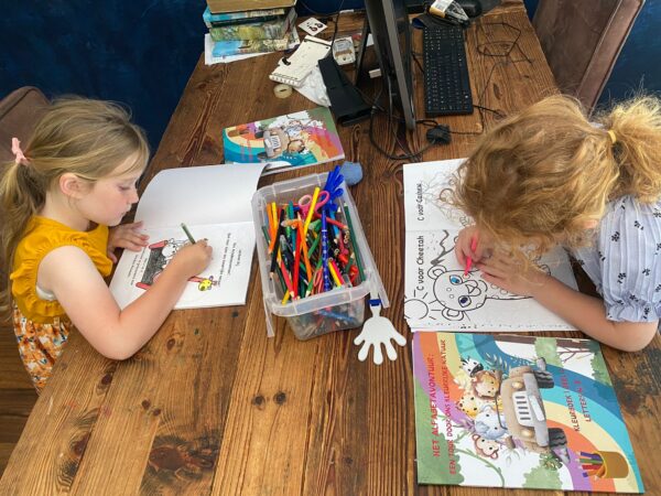 Two children coloring their interactive books from Books by Jonathan, engaging in creative learning.